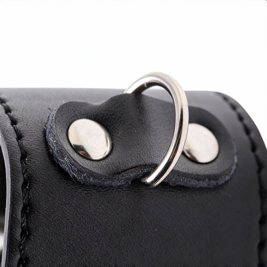 close-up of silver metal d-ring attached to black faux leather ball stretcher with stitched detailing