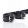 Close-up of the Deluxe Rigid Spreader Bar showing padded faux leather cuffs, reinforced stitching, adjustable buckle closures, and polished metal hardware