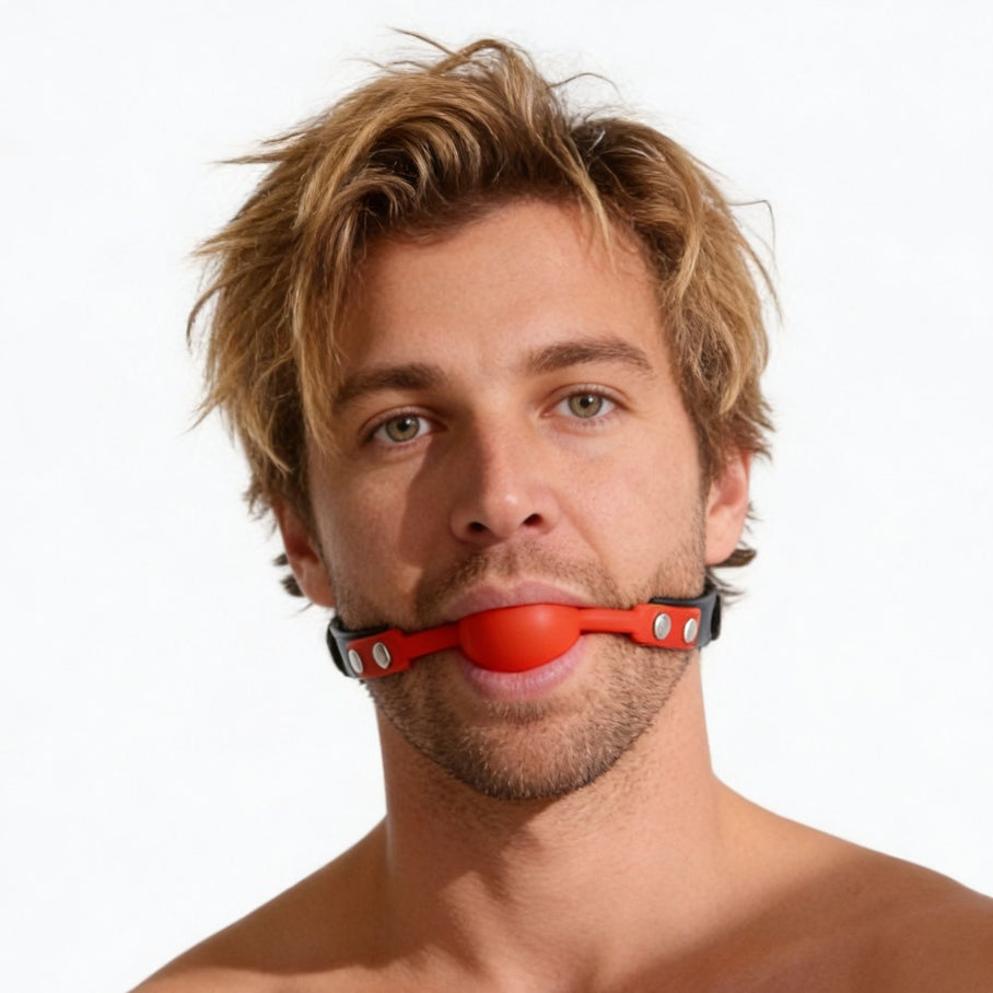 man wearing red silicone comfort ball gag with adjustable black strap and silver hardware